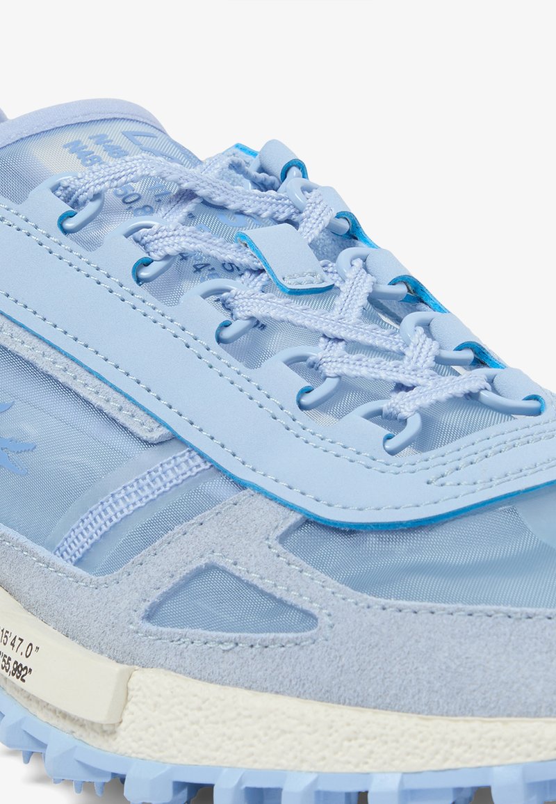 Scarpa sportiva azzurro chiaro con una combinazione di materiali, tra cui rete e pelle scamosciata, con dettagli testurizzati e lacci a contrasto.