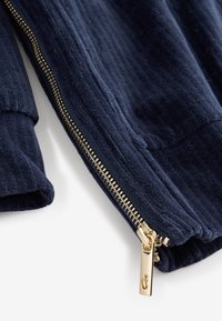 Giacca blu navy con zip, realizzata in tessuto strutturato, con cerniera dorata e cursore liscio, polsini a costine.