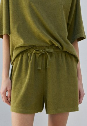 Løse terry-klud shorts i olivengrøn med elastisk talje og snøre, båret med matchende overdimensioneret top med korte ærmer.