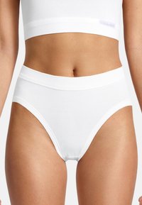 Culottes en coton blanc taille haute avec une ceinture élastique et une texture lisse. Design simple sans motifs ni accents visibles.