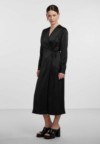 Black satin wrap dress with long sleeves, a V-neckline, and a tie at the waist. Floor-length design and smooth texture.