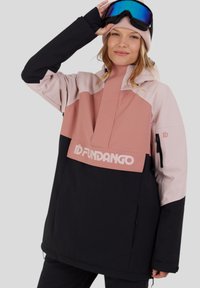 Vrouw die een skibril aanpast, gekleed in een roze, lichtroze en zwarte skijas met het 'Fundango' logo op de voorkant.