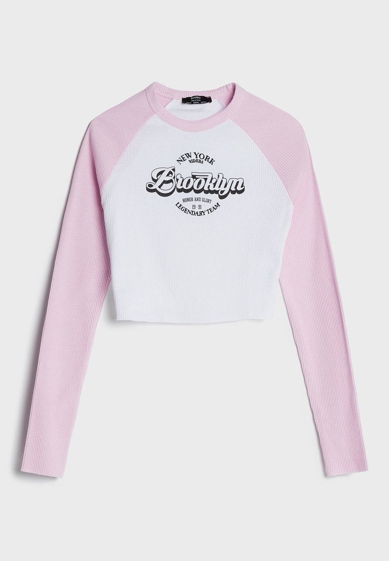 Top a maniche lunghe tagliato con maniche rosa a coste e corpo bianco a coste. Presenta una grafica e testo "Brooklyn" in nero sulla parte frontale.