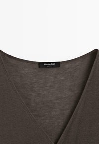 T-shirt marrone a V in morbido tessuto con una leggera texture; presenta un'etichetta con il logo "Massimo Dutti" all'altezza del collo.