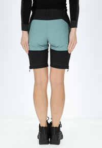 Pantaloni shorts da donna con vita alta, colori a blocchi in blu acquamarina e nero, texture liscia e zip laterali all'orlo. Inclusi calzature nere.