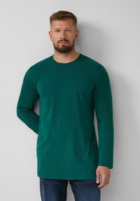 Lange mouwen groen shirt in een soepele katoenmix, met een ronde halslijn en een rechte snit, gecombineerd met donkere jeans.
