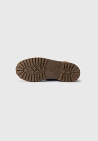 Semelle en caoutchouc brun avec des rainures profondes et logo Timberland, conçue pour une traction et une durabilité en extérieur.