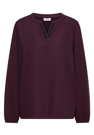 Viininpunainen pitkähihainen pusero, jossa V-aukko, kaulan musta teksturoitu saumakantti ja laskostetut hihansuut. Pehmeä kangas sileällä pinnalla.