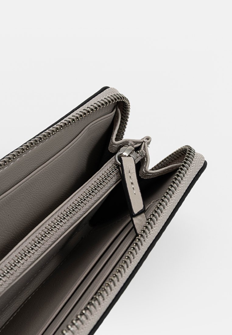 Graue Lederbrieftasche mit schwarzen Akzenten, die über mehrere Fächer und Reißverschlüsse verfügt und eine glatte Textur sowie ein strukturiertes Design aufweist.