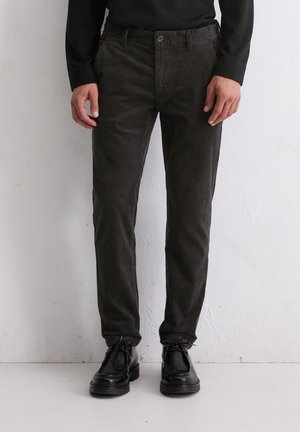 Donkergrijze corduroy broek met een slim fit, voorzien van een knoopsluiting en Franse zakken, gecombineerd met zwarte veterschoenen.