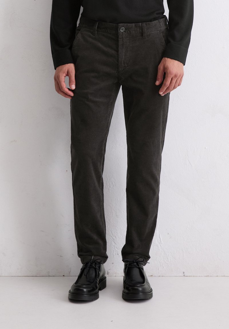 Pantalons en velours côtelé gris foncé à coupe ajustée, dotés d'une fermeture à bouton et de poches avant, associés à des chaussures à lacets noires.