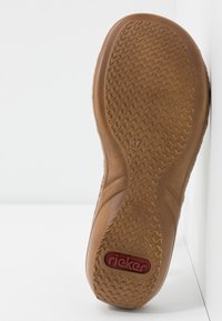 Semelle de chaussure en caoutchouc brun avec un motif texturé, arborant un logo "rieker" rouge et un marquage de taille 37. Bords lisses et design arrondi.