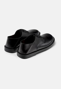 Schwarze Lederschuhe mit glatter Oberfläche, runder Spitze und einer niedrigen matten Sohle. Zu den Merkmalen gehören eine Schnürung mit sechs Ösen.