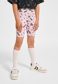 Roze logo-print shorts gemaakt van rekbaar materiaal, gecombineerd met kniehoge witte sokken en zwart-witte sportchoenen.