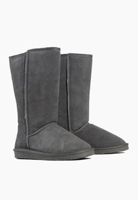 Botas de gamuza gris hasta la mitad de la pantorrilla con puntera redonda, suela de goma plana y costuras visibles a lo largo de las costuras. Diseño simple y sin adornos.