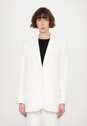 White tailored blazer with a structured design, featuring silver embroidery along the lapels, two front pockets, and large buttons.