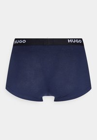 Mornarsko plave bokserice od mekog materijala s crnim elastičnim pojasom na kojem se nalazi bijela oznaka "HUGO". Strukturiran oblik s niskim strukom.