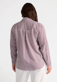 Camisa de manga larga en blanco con rayas verticales burdeos, que presenta un cuello clásico, puños abotonados y un ajuste relajado con detalles de pliegue.