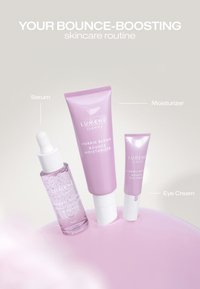 Drie Lumene huidverzorgingsproducten met de labels serum, moisturizer en oogcrème in roze verpakkingen op een lichte achtergrond.