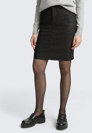 Black denim pencil skirt with front pockets and a smooth finish. Paired with black loafers and sheer black stockings.