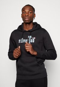 Zwarte hoodie met een voorvak in kangoeroestijl en trekkoord. Voorzien van het "silverTab" logo in wit en lichtblauw. Zachte textuur en casual ontwerp.