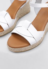 Sandalias de cuña blancas con tiras entrelazadas de material sintético, con una plantilla de imitación de cuero marrón y una suela intermedia envuelta en yute.