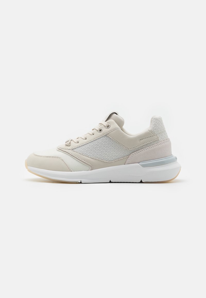Baskets beige et blanches avec panneau latéral texturé, lacets à l’avant, semelle amortissante et subtil accent gris au talon, vues de côté.