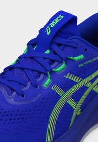 Μπλε παπούτσι τρεξίματος Asics Gel-Cumulus 28 με φωσφορίζουσες πράσινες λεπτομέρειες, κορδόνια και λογότυπο στο διαπνέον επάνω μέρος και τη γλώσσα του παπουτσιού.