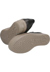 Zapatos de cuero negro con una superficie texturizada y una suela de goma. La suela presenta patrones de agarre circulares y una marca en relieve.