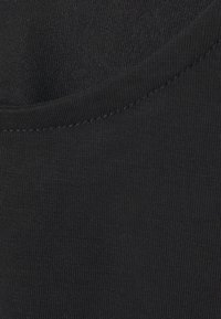 Juodas medvilninis audinys su lygiu paviršiumi. Turi apvalų iškirptę ir plokščius siūlus palei kraštus.