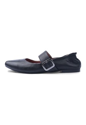 Chaussure plate en cuir noir avec bout pointu, large bride et boucle argentée, et arrière élastiqué pour un maintien sûr.