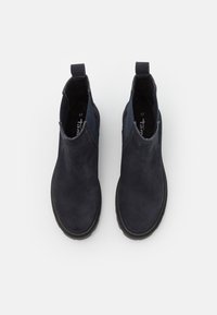 Botas de tobillo de ante azul marino oscuro con textura suave, laterales elásticos y tiradores. Presentan una punta redondeada y una suela de goma para mayor tracción.