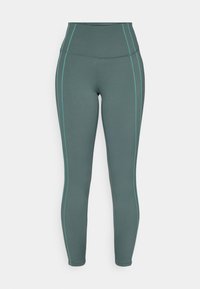 Leggings a vita alta in tessuto verde scuro con cuciture laterali in teal a contrasto, caratterizzati da una texture liscia e un design aderente.