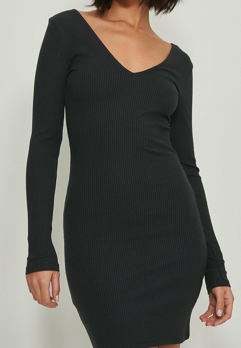 Robe tricotée noire à côtes avec des manches longues et un décolleté en V profond, silhouette ajustée, texture lisse, coupe mi-genoux.