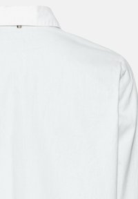 Chemise en lin blanc avec un col classique, texture lisse et un détail de couture discret à l'arrière, conçue pour une coupe décontractée.