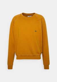 Sudadera amarilla de cuello redondo con mangas largas, puños y dobladillo acanalados, que presenta un pequeño logo bordado en azul en el pecho. Textura de tela suave.