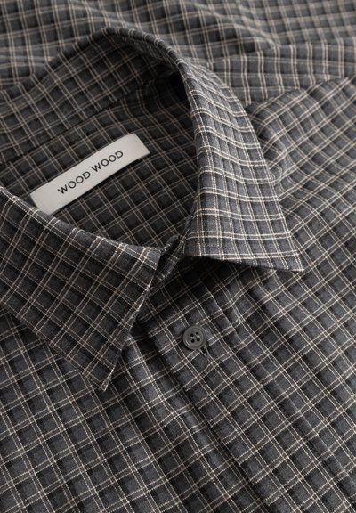 Crna i siva flanelasta košulja na kvadratiće s ovratnikom na kopčanje i bijelom etiketom "WOOD WOOD" te tamnim gumbom.