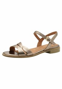 Sandal in bronzo metallico con cinturini incrociati, punta aperta e tacco basso a blocco. Cinturino regolabile alla caviglia con fibbia. Texture in pelle liscia.