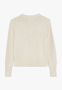 Krémový pletený svetr s žebrovaným lemem a manžetami, s volným střihem a texturovaným vzorem na zadní straně.