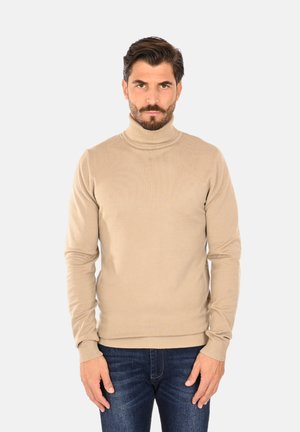 Maglione beige a collo alto, tessitura a coste, design attillato, maniche lunghe, abbinato a jeans blu per un look casual.