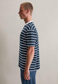 T-shirt rayé bleu marine et blanc, à manches courtes avec un col rond, en tissu texturé et avec des fentes sur les côtés à l'ourlet pour plus de liberté de mouvement.