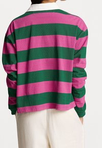 Gestreifter Pullover in Rosa und Grün, mit lockerer Passform, langen Ärmeln und einem weißen Kragen. Weicher Stoff mit glatter Textur.