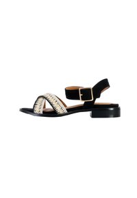 Black suede sandal with a low block heel, featuring a woven gold and off-white detail across the front and an adjustable ankle strap.