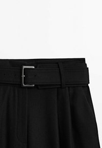 Zwarte broek met een gestructureerde tailleband, voorzien van een zilveren metalen gesp en gestikte naden, met een gladde textuur en een op maat gemaakte uitstraling.
