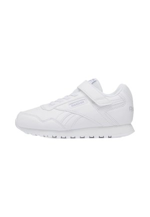 Zapatilla blanca de Reebok con cierre de velcro, lengüeta de malla y suela texturizada, mostrada de perfil sobre un fondo blanco.