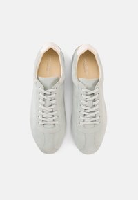 Αθλητικά παπούτσια από σουέντ σε ανοιχτό γκρι χρώμα με στρογγυλεμένη μύτη, κλασικό σχέδιο με κορδόνια και κρεμ λεπτομέρειες στη φτέρνα και στη γλώσσα. Λείο εσωτερικό επένδυση.