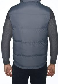 Dunkelgraue Steppweste mit hohem Kragen und gestepptem Muster, kombiniert mit grauen Strickärmeln und einer taillierten Passform.