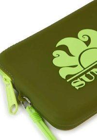 Custodia in silicone verde con logo a forma di sole in verde chiaro, dotata di zip e attacco a loop. Superficie testurizzata con finitura liscia.
