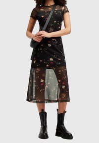 Musta kukkakirjailtu verkomekko lyhyillä hihoilla, kerroksellinen muotoilu, läpikuultava hame ja pikkukukkakuvio. Yhdistetty mustien nilkkureiden ja olkalaukun kanssa.