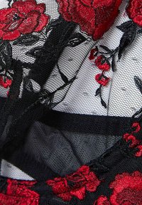 Svart spetstyg med röd blommönstring och delikat svart nät. Innehåller mjuk textur och intrikata detaljer i blommönster.